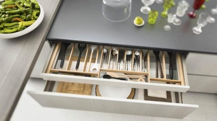 Detalle de interior de cajón para cubiertos acabados en madera y blanco.