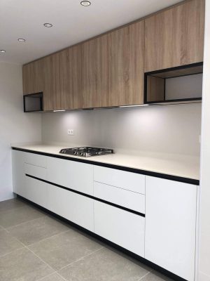Muebles de cocina con una configuración en paralelo. Material laminado, combinación de madera y blanco seda.